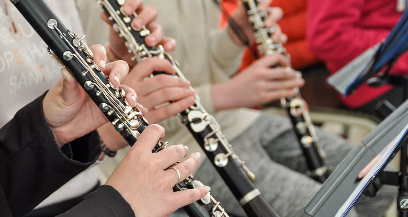 Drei Menschen spielen Klarinette, man sieht hauptsächlich deren Hände. 
