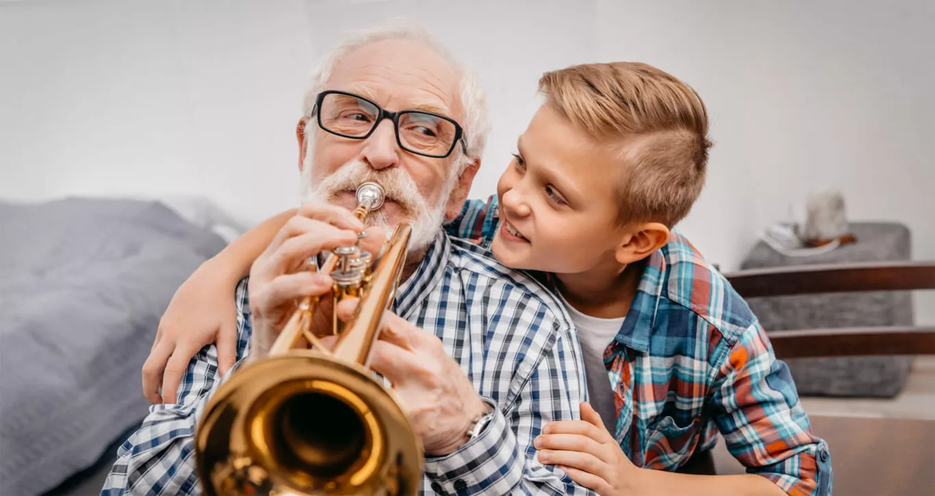 Der Enkel schaut seinem Großvater beim Trompete-Spielen über die Schulter.