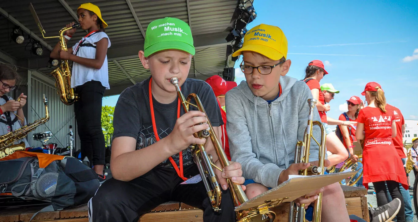 Zwei Jungen spielen im Sitzen Trompete.